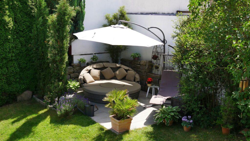 Gartenecke mit Loungegruppe unterm Sonnenschirm und umgeben von diversen Pflanzen