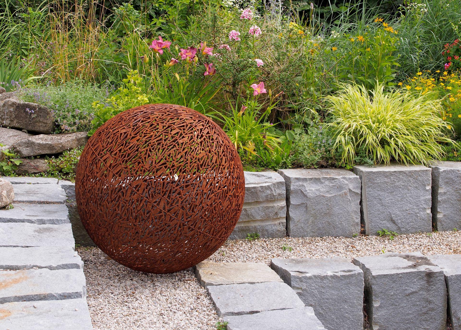 Rostige Kugel als Gartenstecker im Steinbeet