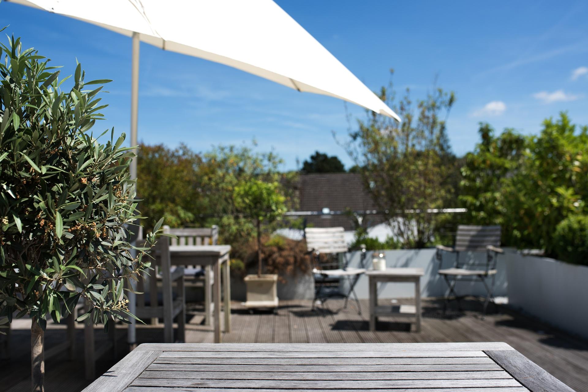 Weiße Terrasse mit Holzstühlen | wasserdurchlässige Sonnensegel